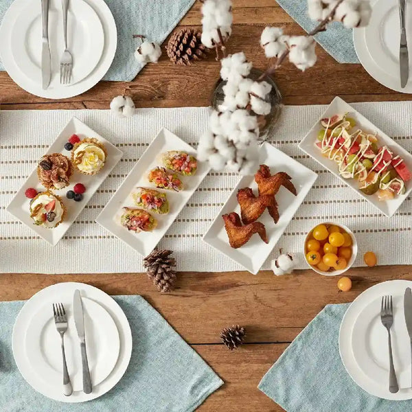 Dining table set with plates of food, cutlery, and decorative elements on a wooden surface.