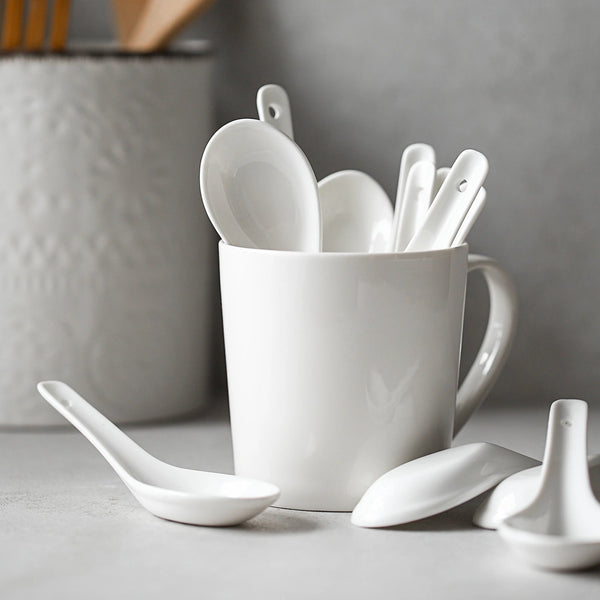 White ceramic spoons in a white mug on a gray surface