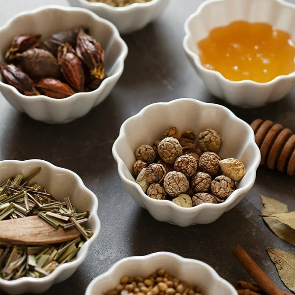 Assorted herbs and spices in white bowls on a dark surface