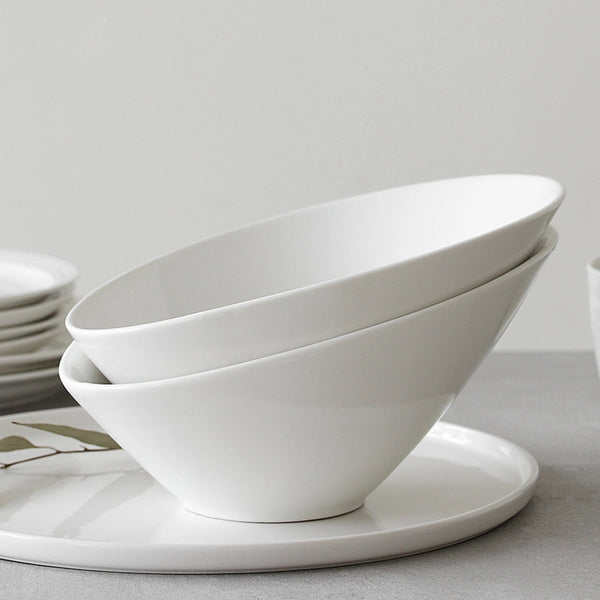 Stack of white ceramic bowls on a light gray surface with a neutral background