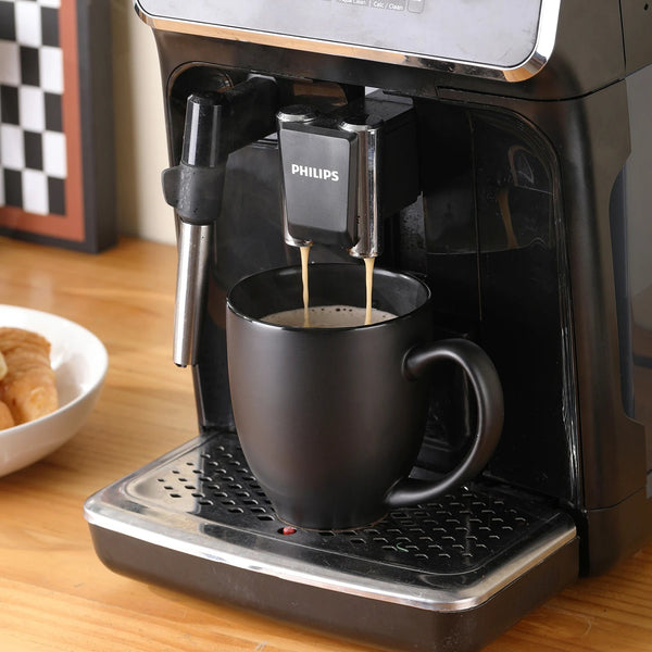 A stream of coffee flows from the machine into coffee mug matte black