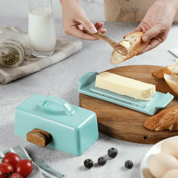 Teal butter spreader with wooden handle on a kitchen counter with bread and butter.