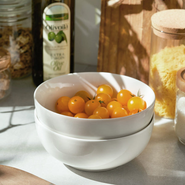 White bowls filled with yellow berries on a table with jars in the background