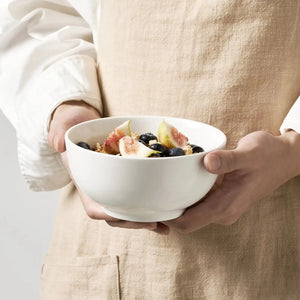 Person holding a white cereal bowl of fruit and granola