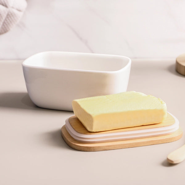 Bar of soap on a wooden soap dish with a white ceramic soap holder in the background.