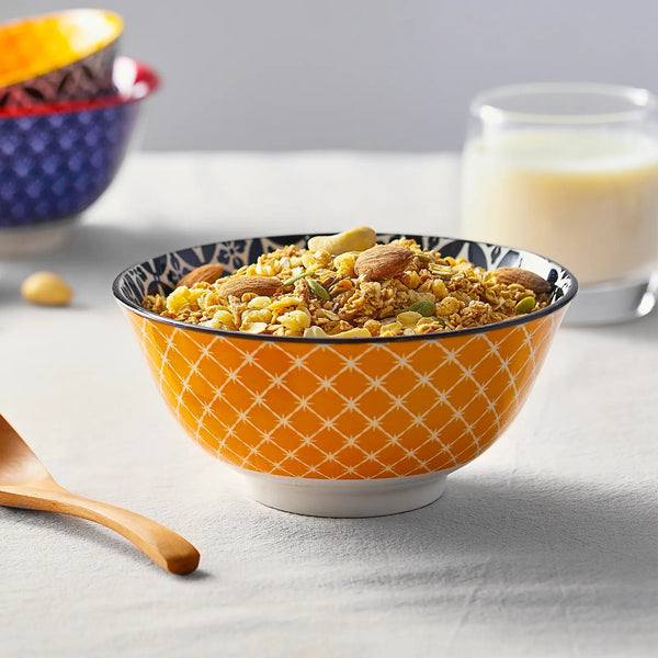 Orange bowl with cereal and nuts on a light gray surface