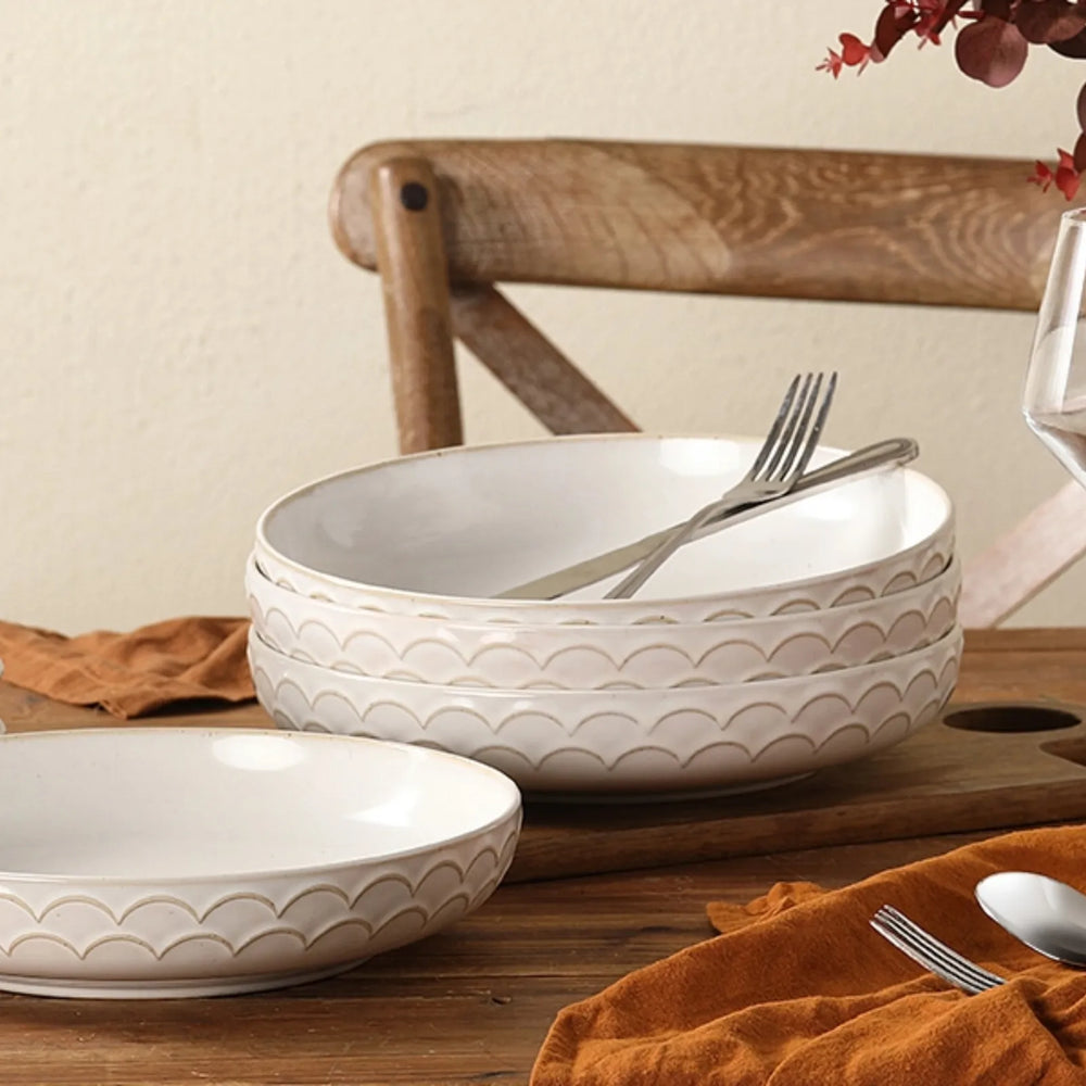 Set of four stoneware pasta bowls with wave pattern on a white background