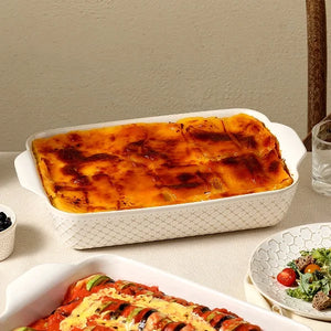 Baked dish in a white rectangular baking dish on a table with a side of salad.