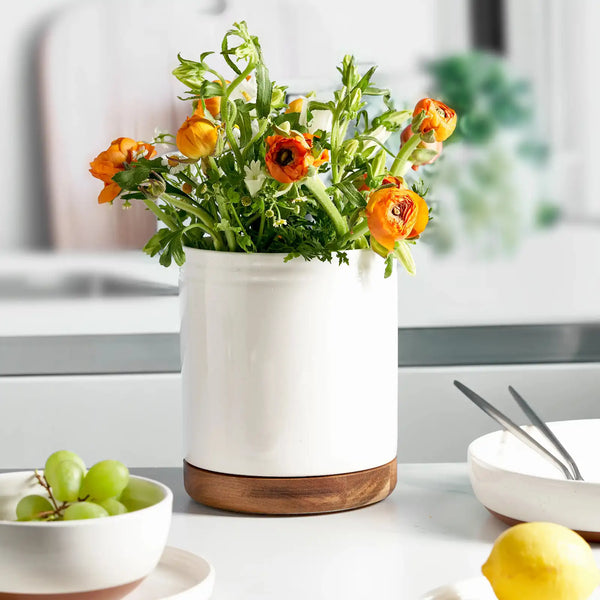 White ceramic rotating utensil holder with orange flowers on a kitchen counter