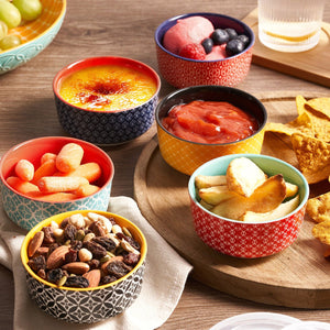 Assorted snacks in colorful bowls on a wooden table