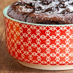 Chocolate cake in a red and white patterned bowl on a wooden surface