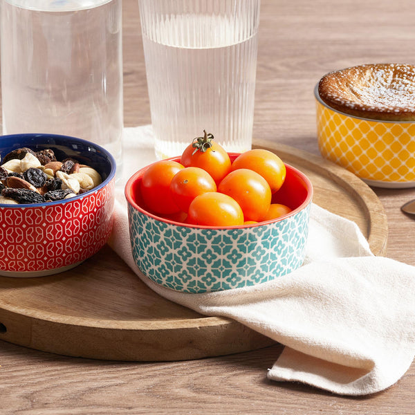 Two patterned bowls on a wooden tray with tomatoes and dried fruits.