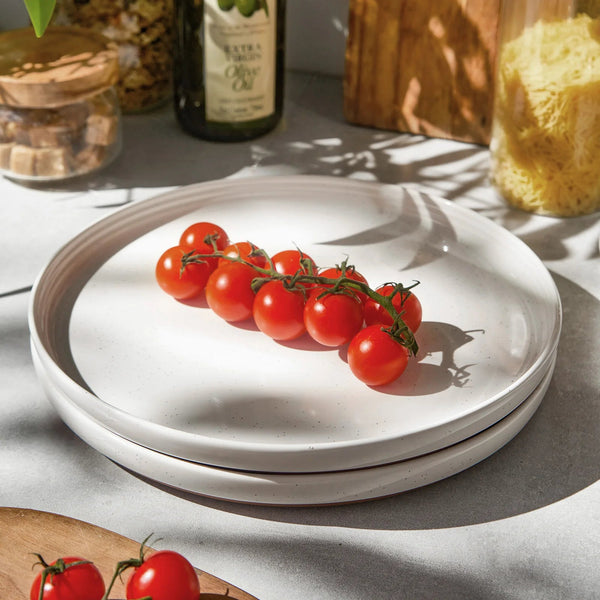 White ceramic plates with cherry tomatoes on a light gray surface