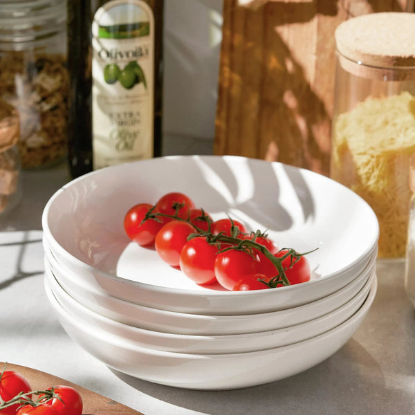 Stack of white bowls with cherry tomatoes on a kitchen counter