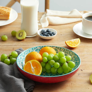 Fruit bowl with grapes and oranges on a wooden table with milk, blueberries, and a cup.