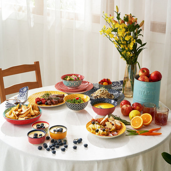Diverse food items on a table with a vase of flowers and apples.