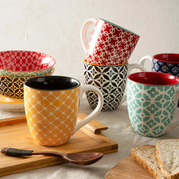colorful coffe  mugs and bowls on a table with a wooden spoon and bread slices.