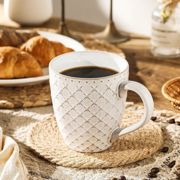 ceramic handmade mug with coffee on a wooden table with pastries and coffee beans.