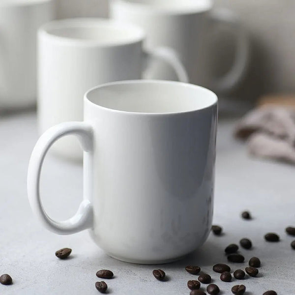 White mug on a surface with coffee beans around it