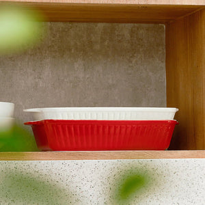 Red and white ceramic dishes on a wooden shelf with a neutral background