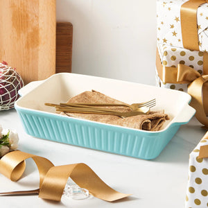 blue baking dish with gold forks and napkins on a white surface with gift-wrapped items in the background.