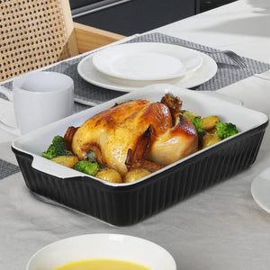 Roasted chicken with vegetables in a black baking dish on a dining table.
