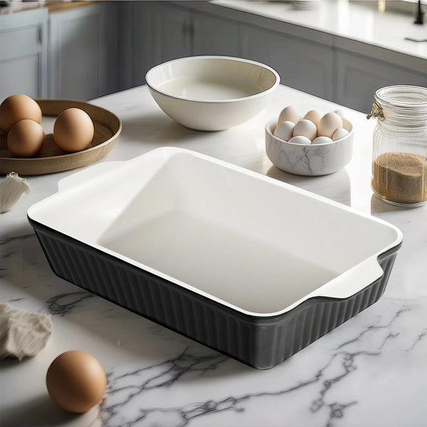 Black rectangular baking dish on a marble countertop with eggs and bowls.