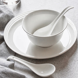 White ceramic bowl and spoons on a gray surface