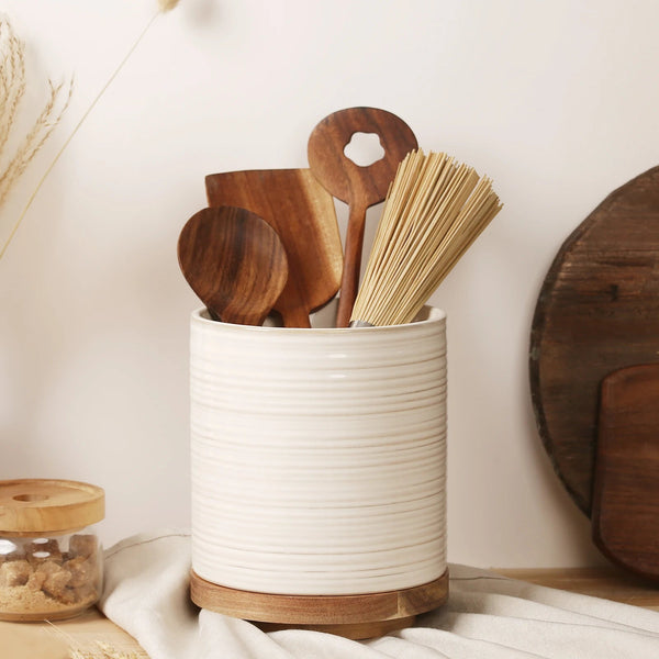 White ceramic container with wooden utensils on a neutral background