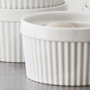 White ceramic ramekins with ribbed texture on a gray surface