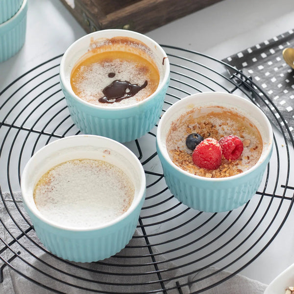 Three small baked desserts in turquoise ramekins on a cooling rack.