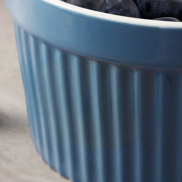 Blue ceramic ramekin with ribbed design on a neutral background