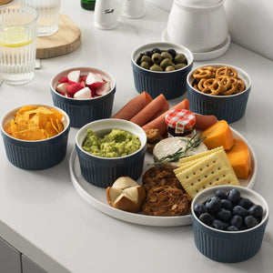 Assorted snacks in small ramekins on a white surface