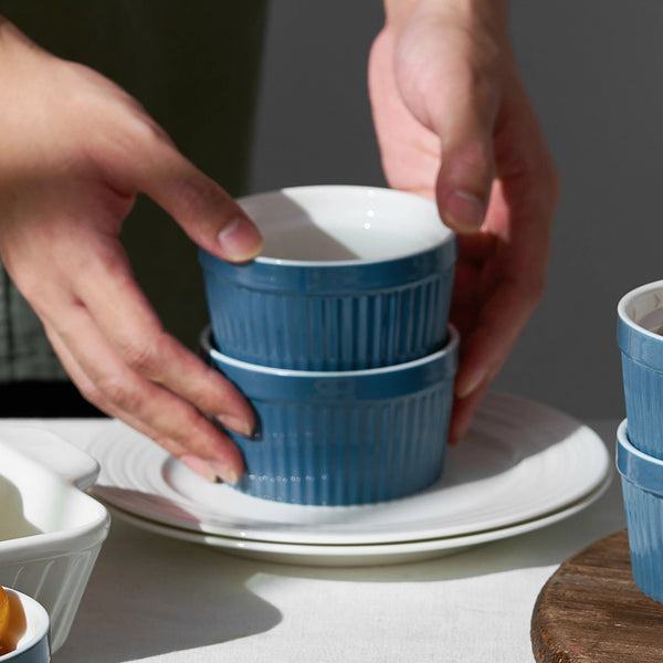 Stack of blue ceramic bowls being held by a person on a neutral background
