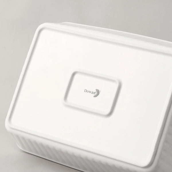 White ceramic baking dish with a lid on a gray background